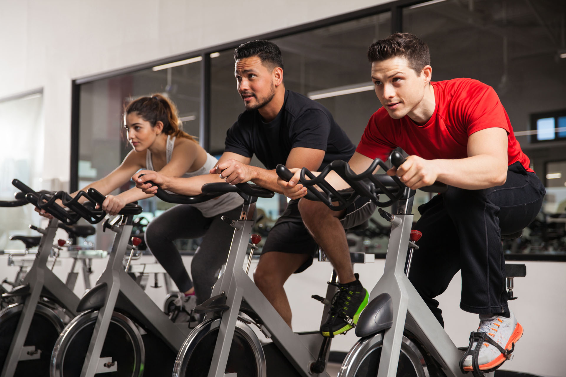 Three young people doing some cardio and acting all focused during their spinning class