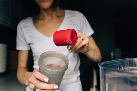woman adding protein to smoothie
